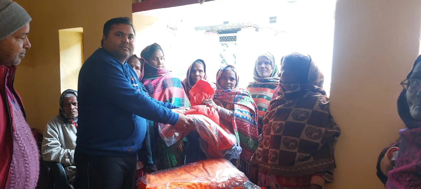 Pankaj distributing blankets during a community gathering in Kushinagar