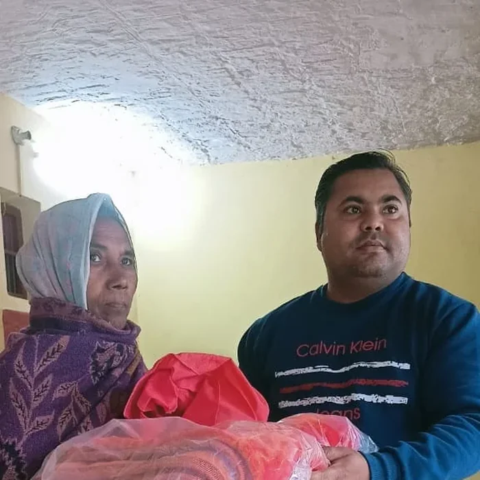 Pankaj handing a blanket to a woman
