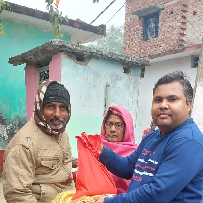 Pankaj distributing a blanket outdoors in Kushinagar