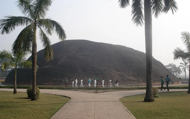 Ramabhar Stupa in Kushinagar surrounded by palm trees and walking pilgrims